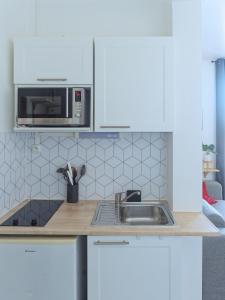 kuchnia ze zlewem i kuchenką mikrofalową w obiekcie L'escale cosy - Nogent Le Rotrou - Proche gare w mieście Nogent-le-Rotrou +2 zdjęcia