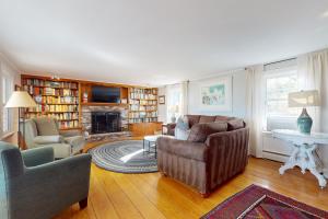 ein Wohnzimmer mit Sofa und Stühlen und einem Kamin in der Unterkunft Cape Landing Cottage in Brewster