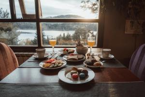 a table with plates of food and drinks and a window at Boutique Hotel & Spa Bosque del Nahuel in San Carlos de Bariloche