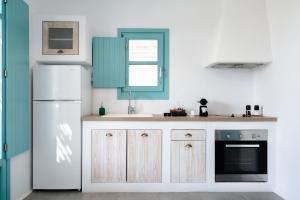 a kitchen with a white refrigerator and a sink at Ploes Seaside Houses in Plaka
