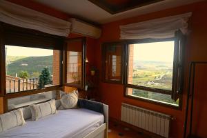 a bedroom with two windows and a bed with white sheets at Casa Rural El Mirador de la Vega in Horche