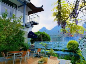 um pátio com mesas e cadeiras e vista para as montanhas em Guilin Tranquil Peaks Retreat by Reed Flute Cave em Guilin
