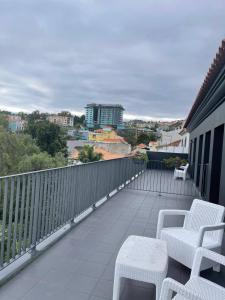 een balkon met witte stoelen en uitzicht op de stad bij Carreira Residence in Funchal