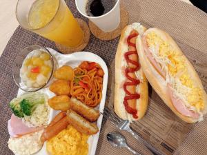 une table avec une assiette de nourriture avec un hot-dog et des pommes de terre dans l'établissement Hotel -ASIATO-, à Osaka
