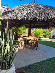 un patio con mesa, sillas y sombrilla de paja en Pousada Villa Kalani, en Timbó