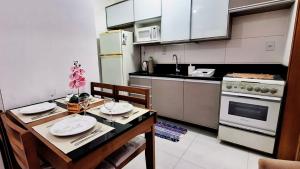a kitchen with a table and a kitchen with a stove at 400m da Praia II 1,7km 61ª Congresso Mercado & Congresso Est Católica 2025 ll Wi Fi 750 Mpbs ll Churrasqueira ll 2ºAndar Elevador ll Ar Condicionado ll Maquina de Lavar ll Vaga Para Carro ll Guarda Sol l Cadeiras de Praia in Tramandaí
