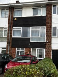 Un coche rojo aparcado delante de un edificio en Elm Park Home with Garden & Parking, en Hornchurch