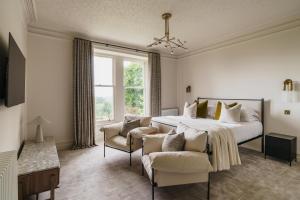 a bedroom with a bed and two chairs and a window at Beaumont Exquisite Lakeland House, Sleeps 10 in Windermere