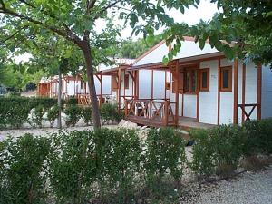 Casa blanca con porche y árbol en Camping Bungalows Mariola, en Bocairent