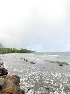 a beach with rocks and the ocean on a cloudy day at Teahupoo MANA VILLA in Toanoano +3 photos