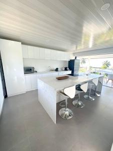 a kitchen with white cabinets and a counter with stools at Teahupoo MANA VILLA in Toanoano