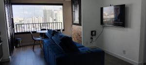 a living room with a blue couch and a balcony at Apto Resort Brás Piscina, Ar-condicionado in São Paulo