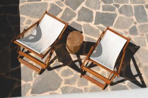 two wooden chairs sitting on a stone floor at Ploes Seaside Houses in Plaka