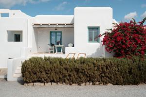 a white house with red flowers in front of it at Ploes Seaside Houses in Plaka