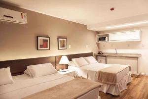 a hotel room with two beds and a kitchen at Hotel Atmosfera Feira de Santana in Feira de Santana