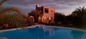 a villa with a swimming pool in front of a building at La Siwa in Siwa