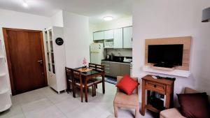 a living room with a dining table and a kitchen at 400m da Praia II 1,7km 61ª Congresso Mercado & Congresso Est Católica 2025 ll Wi Fi 750 Mpbs ll Churrasqueira ll 2ºAndar Elevador ll Ar Condicionado ll Maquina de Lavar ll Vaga Para Carro ll Guarda Sol l Cadeiras de Praia in Tramandaí