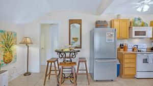 a kitchen with a refrigerator and a table with stools at Suzys Parrot Perch by Last Key Realty in Key West