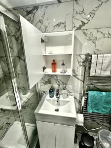 a white bathroom with a sink and a shower at Timex Studio in Croydon