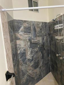 a bathroom with a shower with a stone wall at Bonito Departamento Amueblado y se factura in Guaymas