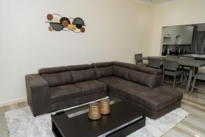 a living room with a brown couch and a table at Luxe Oasis Villas - Lusaka in Kenneth Kaunda International Airport