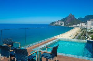a balcony with chairs and a swimming pool and a beach at Sol Ipanema Hotel in Rio de Janeiro