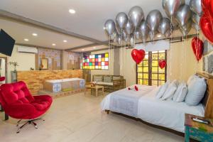 a bedroom with a bed and a red chair and balloons at NQ Hotel Orinoquia in Villavicencio