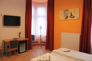 Cette chambre comprend un lit, un bureau et une fenêtre. dans l'établissement Hotel Weidenhof, à Düsseldorf