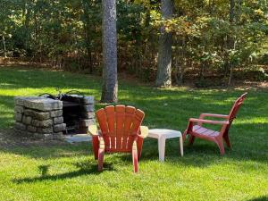 two chairs and a table and a bench in the grass at Walk to Water Gorgeous Outdoor Space in Eastham