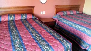 dwa łóżka siedzące obok siebie w pokoju w obiekcie Two Palms Motel w mieście Glendale