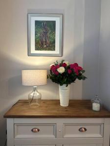 a table with a lamp and a vase with flowers on it at Royal Hillsborough Hideaway in Hillsborough