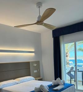 a bedroom with two beds and a ceiling fan at Hotel Roca Bella in Es Pujols
