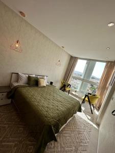 Appartement moderne avec vue panoramique في أغادير: غرفة نوم بسرير اخضر ونافذة كبيرة