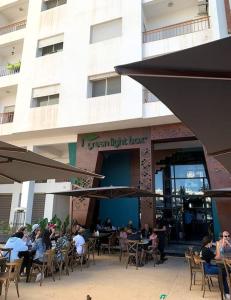 Appartement moderne avec vue panoramique في أغادير: مجموعة من الناس يجلسون على الطاولات أمام المبنى