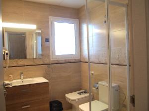 a bathroom with a toilet and a sink and a window at Hotel Roca Bella in Es Pujols