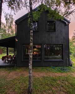 a black house with a tree in front of it at Dom U Piepki in Zdunowice Małe