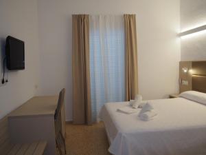a hotel room with two beds and a television at Hotel Roca Bella in Es Pujols