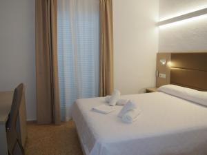 a hotel room with a bed with two towels on it at Hotel Roca Bella in Es Pujols