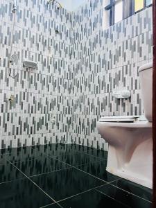 a bathroom with a toilet and a tiled wall at Les Résidences Terre Royale in Sokouhoué +40 photos