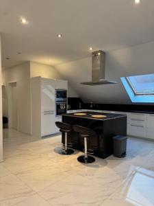 a kitchen with a black counter and stools at Modernes Apartment in Wald- und Stadtnähe in Rieneck
