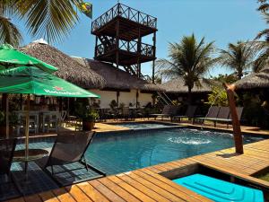 a swimming pool with chairs and an umbrella next to a resort at Atins Charme Chalés in Atins