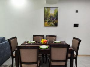 a dining room table with chairs and a painting on the wall at Lola's Haven - 75" Screen, Heated Pool, Gym, Views in Nairobi