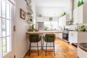 a kitchen with white cabinets and green bar stools at Ivy Grace - 4 Br, Stylish, Pet-friendly Retreat in Indianapolis