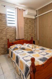 Un dormitorio con una cama con una colcha encima en Tout confort à proximité de tout, en Case-Pilote