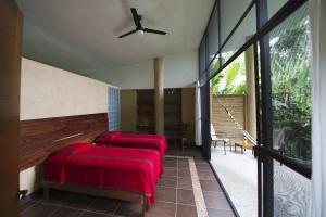 a bedroom with two red beds and a ceiling fan at Canto de la Selva Jungle Lodge Selva Lacandona Chiapas in Galaxia