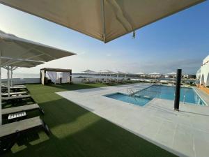 a swimming pool with a large umbrella on top of a building at Hotel Roca Bella in Es Pujols