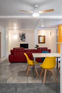 una sala de estar con un sofá, una mesa y sillas en Tout confort à proximité de tout, en Case-Pilote
