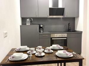 a kitchen with a wooden table with plates and cups at NEU Große Einzimmerwohnung im Zentrum Goldstadt Pforzheim Schlössle in Pforzheim +69 photos