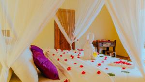 Una cama con cortinas blancas y un pastel. en Moyo Mzuri Villas Resort Zanzibar, en Migogoni