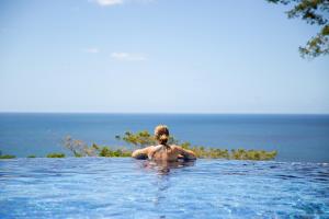 a woman sitting in a swimming pool in the ocean at Mount Edgecombe Boutique Hotel in Maran